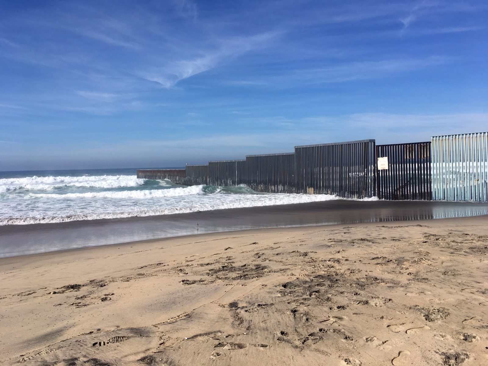 a wall juts out into the ocean dividing Tijuana, Mexico, and San Diego, California