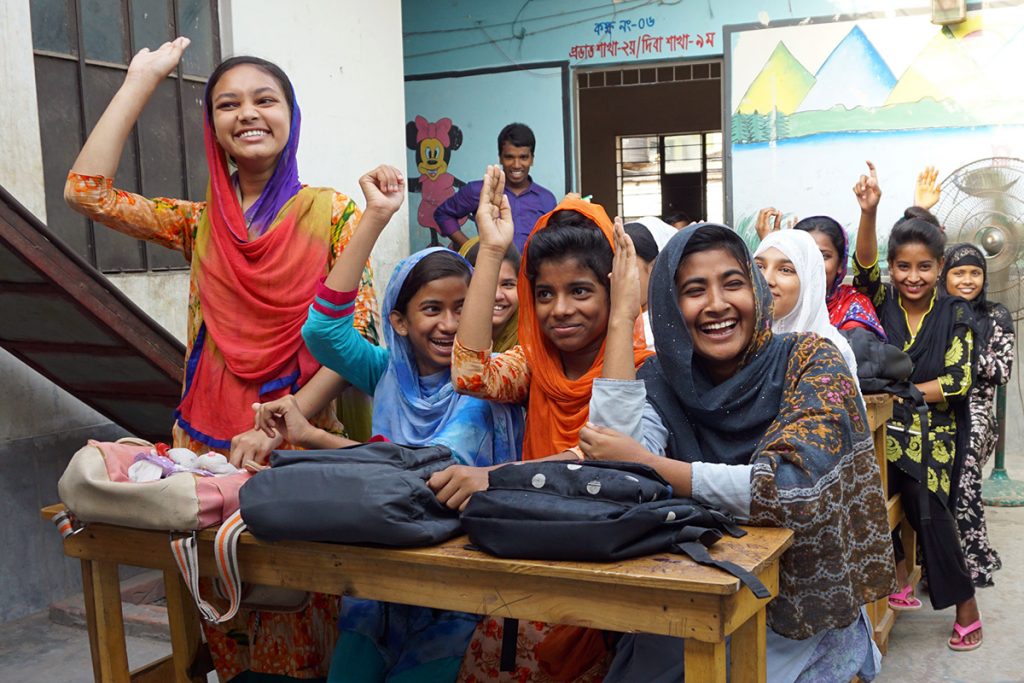 Bangladeshi girls raise their hands in a classroom at APON