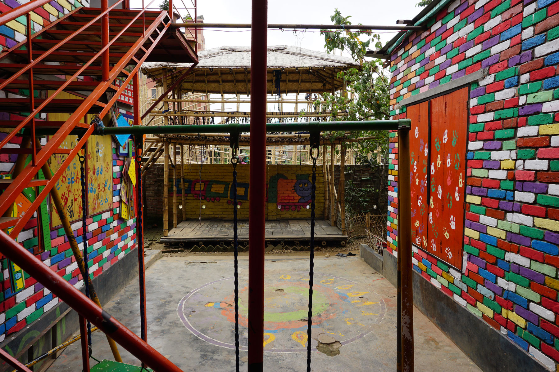 Colored tiles, a swing set, and red stairs line LEEDO's indoor patio. © Global Fund for Children
