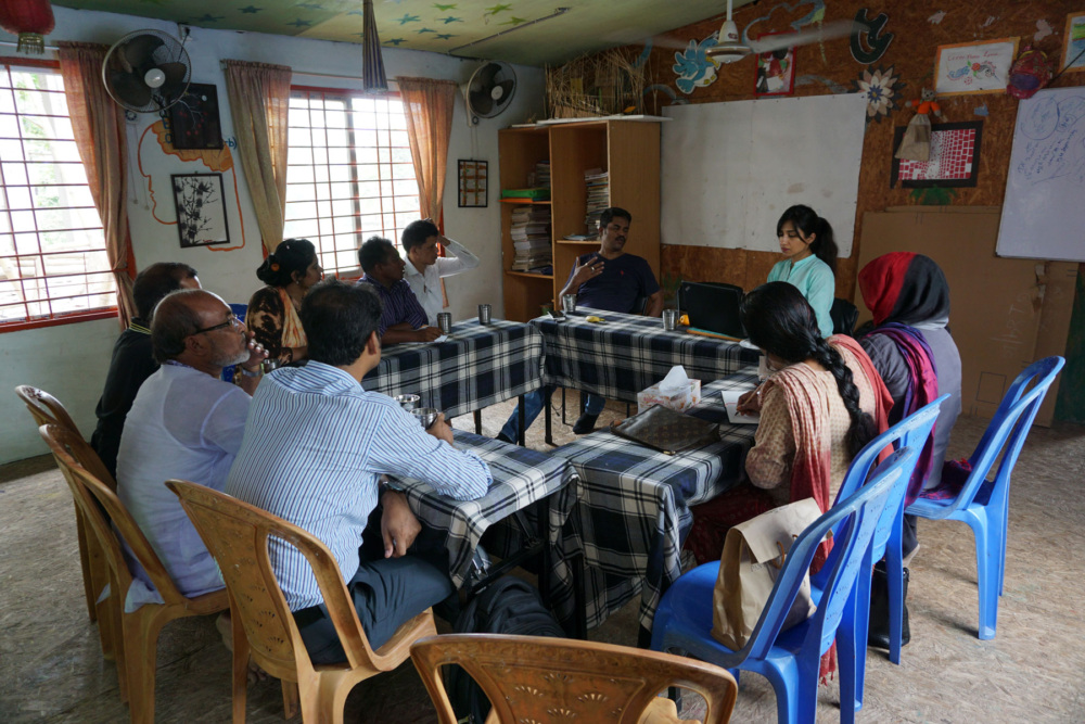 LEEDO and GFC staff members sit around tables in a circle in a meeting. © Global Fund for Children