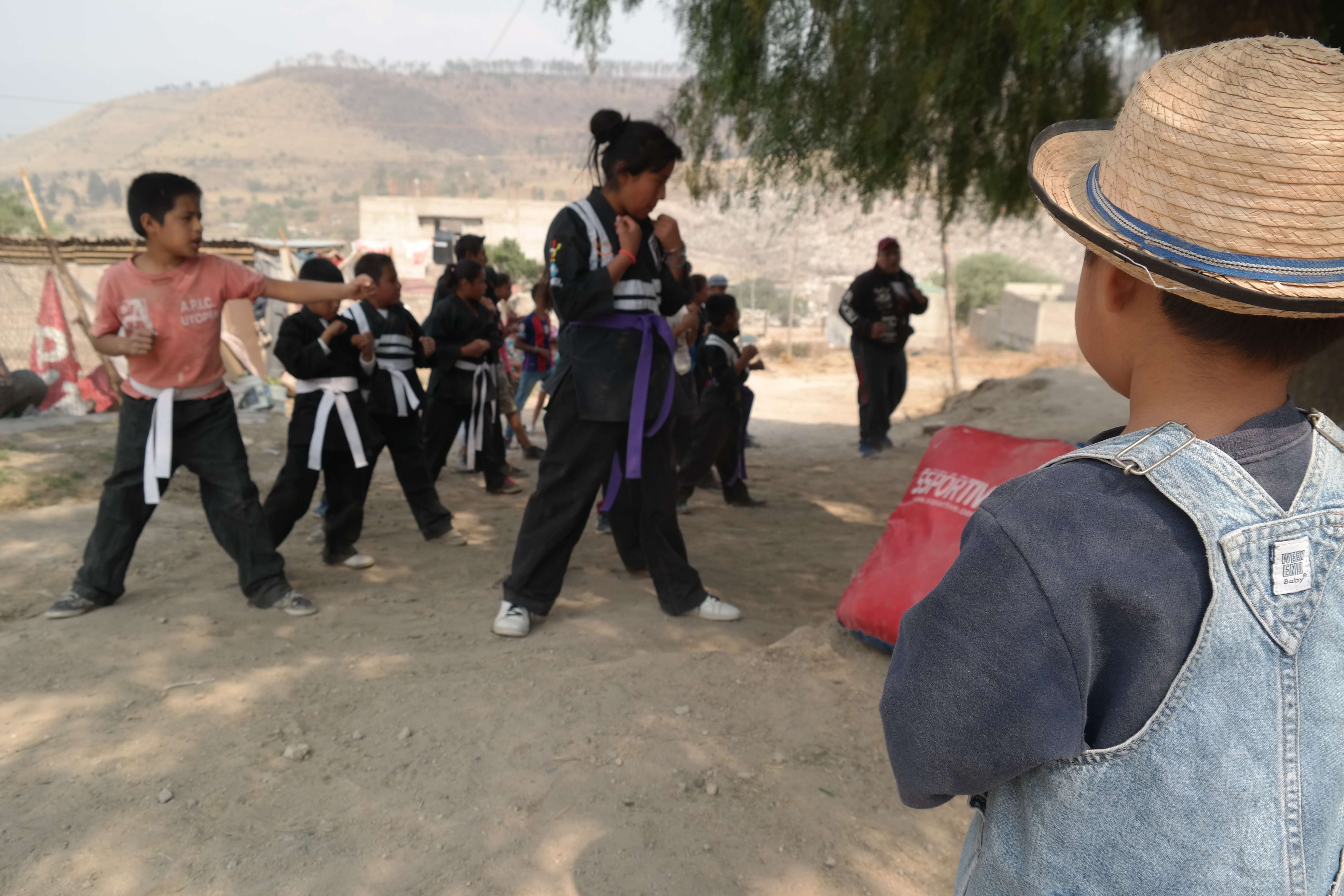 Young boy from the community watching other youth practice martial arts. 