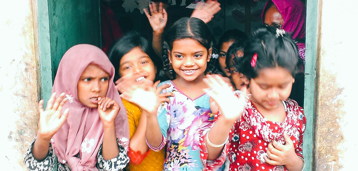 Bangladeshi girls raise their hands in a classroom at APON