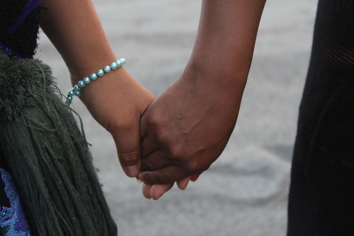 A close up of two people holding hands.