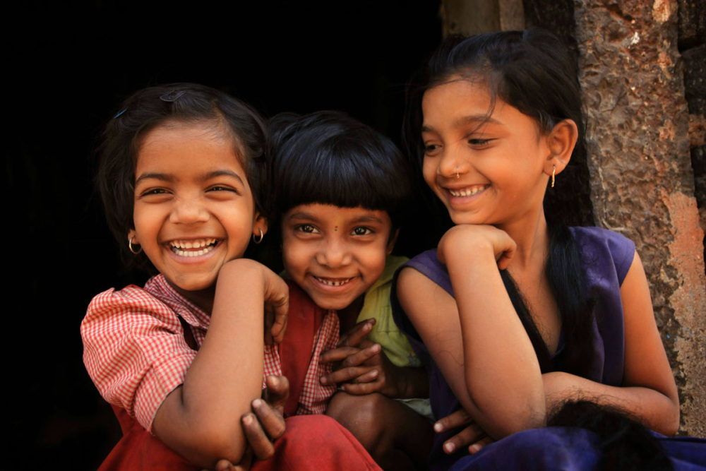 Three girls sit laughing.