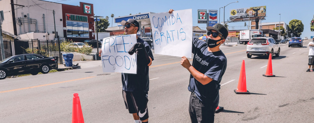 Homies Unidos youth hold up "Free Food" signs at a Community Response Initiative event.