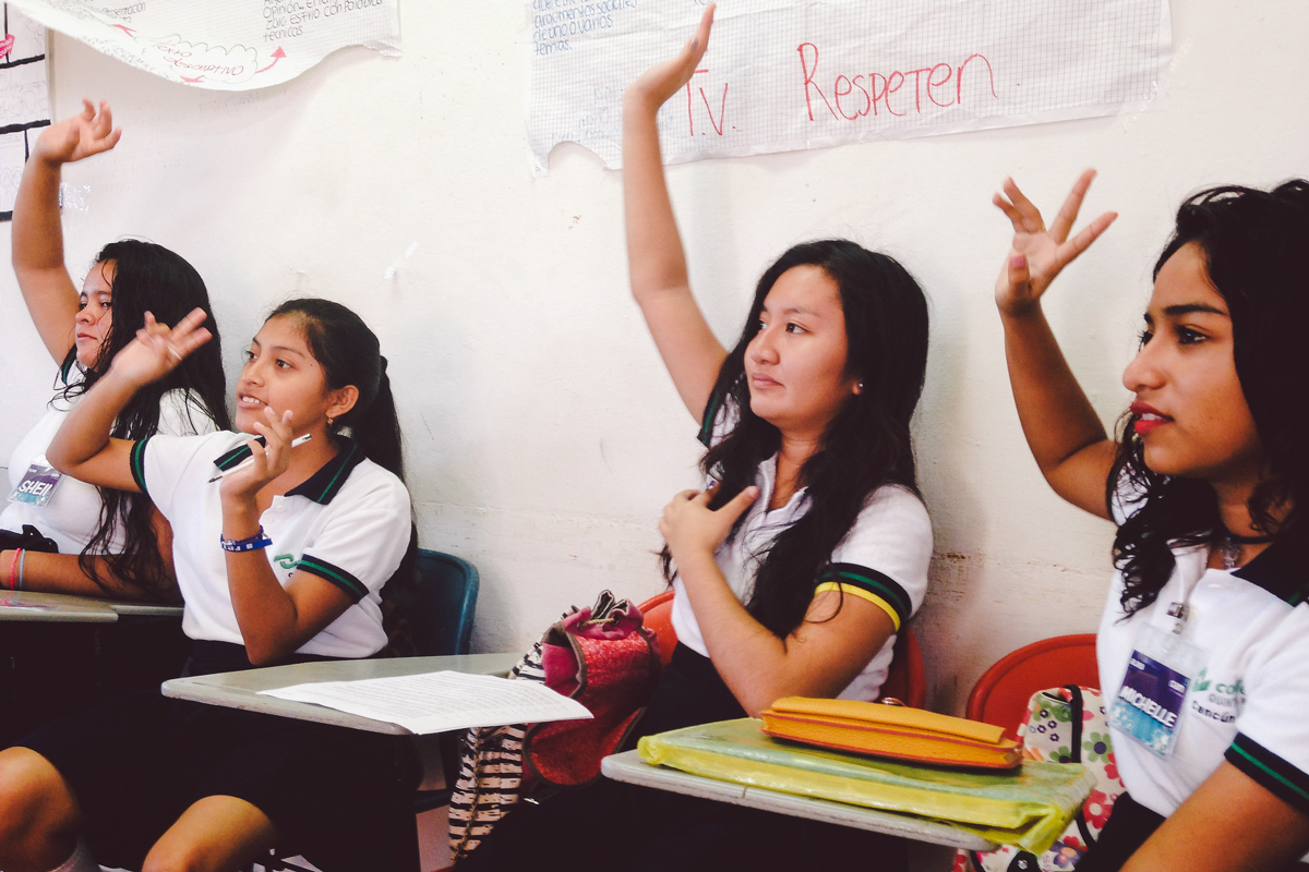 Girls raise their hands in a classroom