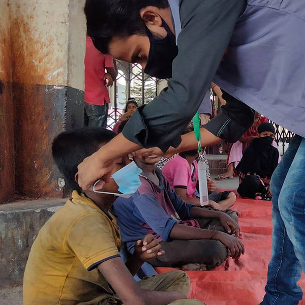 An outreach worker helping a child put on a mask