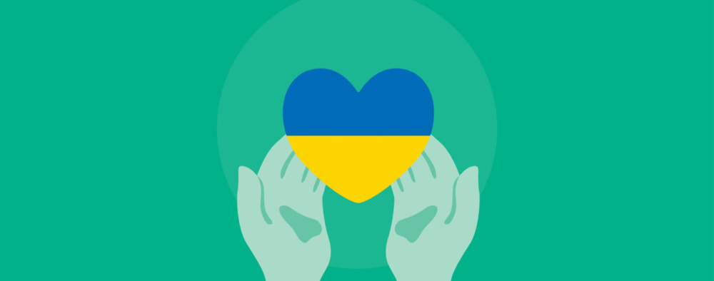 Green hands holding a heart with the colors of the Ukrainian flag