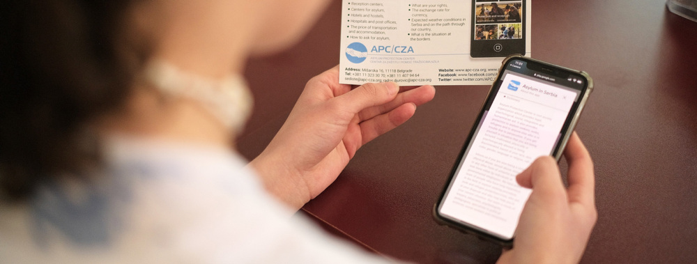 A woman holding a phone and flyer