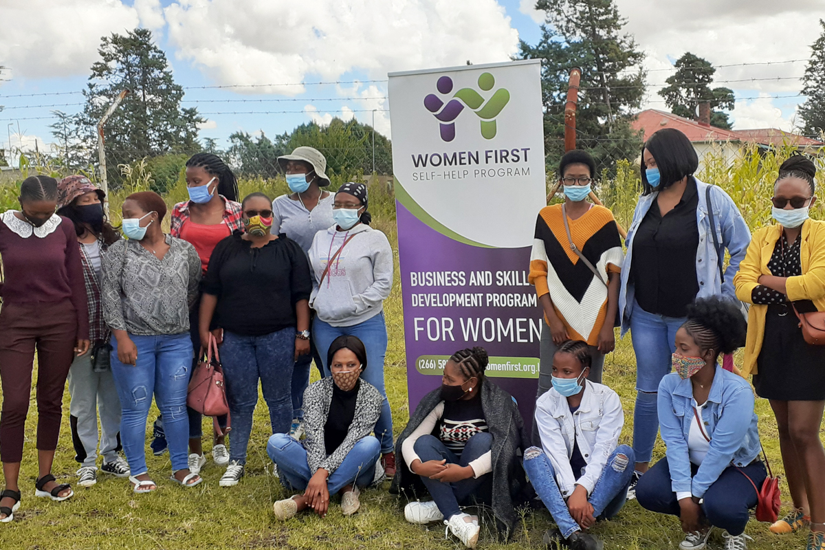A group photo next to a Women First Self-Help Program sign