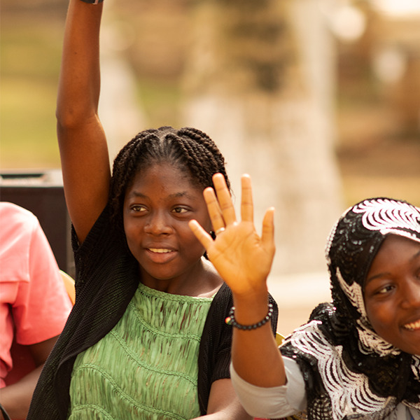 Two girls with their hands raised at West Africa Adolescent Girls Summit, 2022.