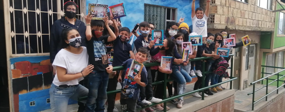 Children holding up decorated picture frames from an art workshop carried out by Centro Cultural Popular Victor Jara in Usme, Bogotá.