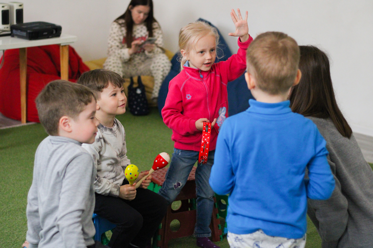 A small group of children playing with some musical instruments.