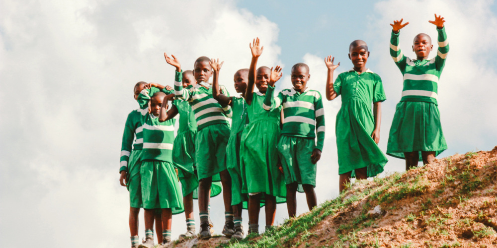 A group of girls standing atop a hill, waving.