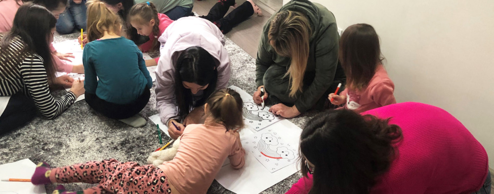 Children sprawled on the floor, drawing