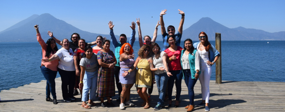 A group of people - GFC partners and staff - posing for a picture with against a backdrop of volcanos in Guatemala