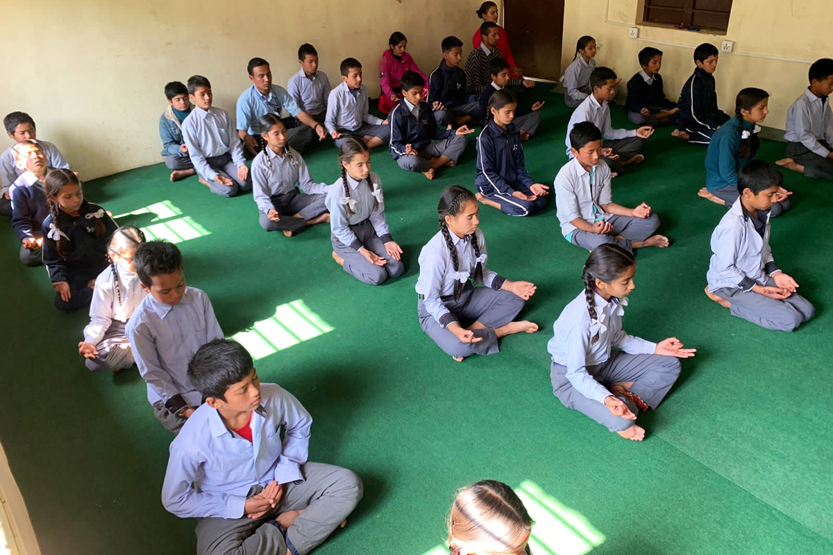 Children seated cross-legged, meditating. 