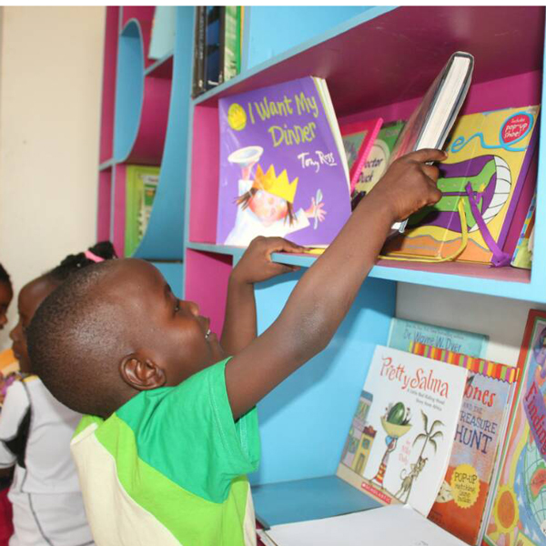 A child reaching for a book on a shelf