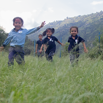 Children playing in grass and running towards camera.
