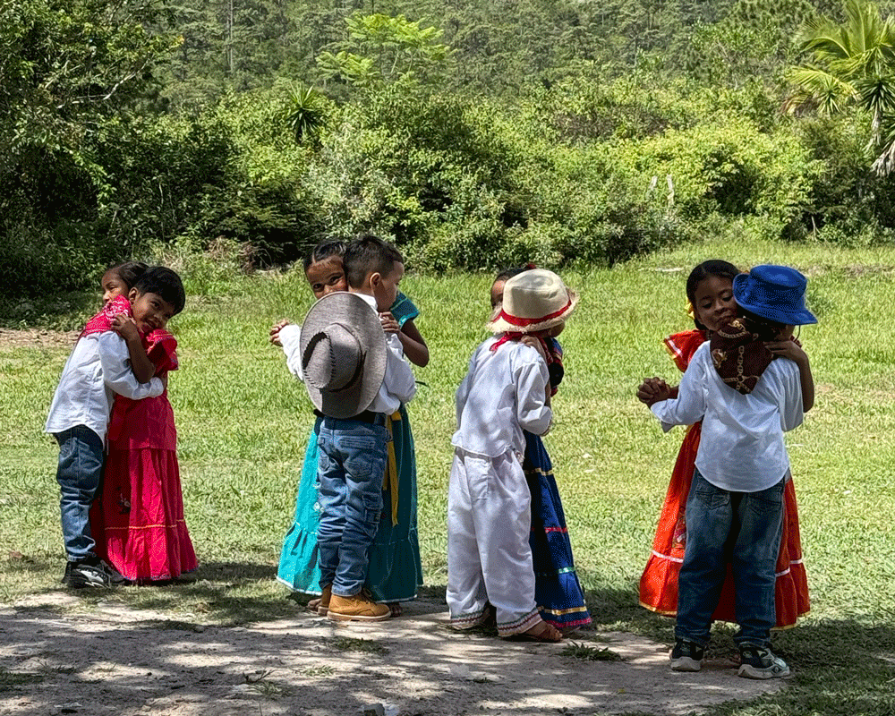 4 sets of children in colourful costumes, dancing in couples 
