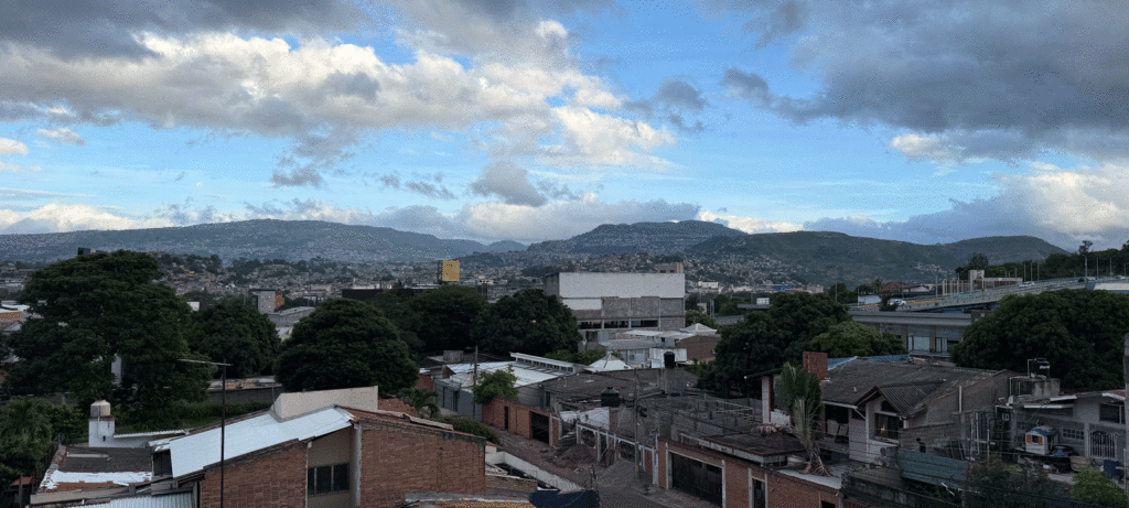 A landscape of the mountains in the far distance beneath blue skies seen through the Honduran city of Tegucigalpa with lots of housing 